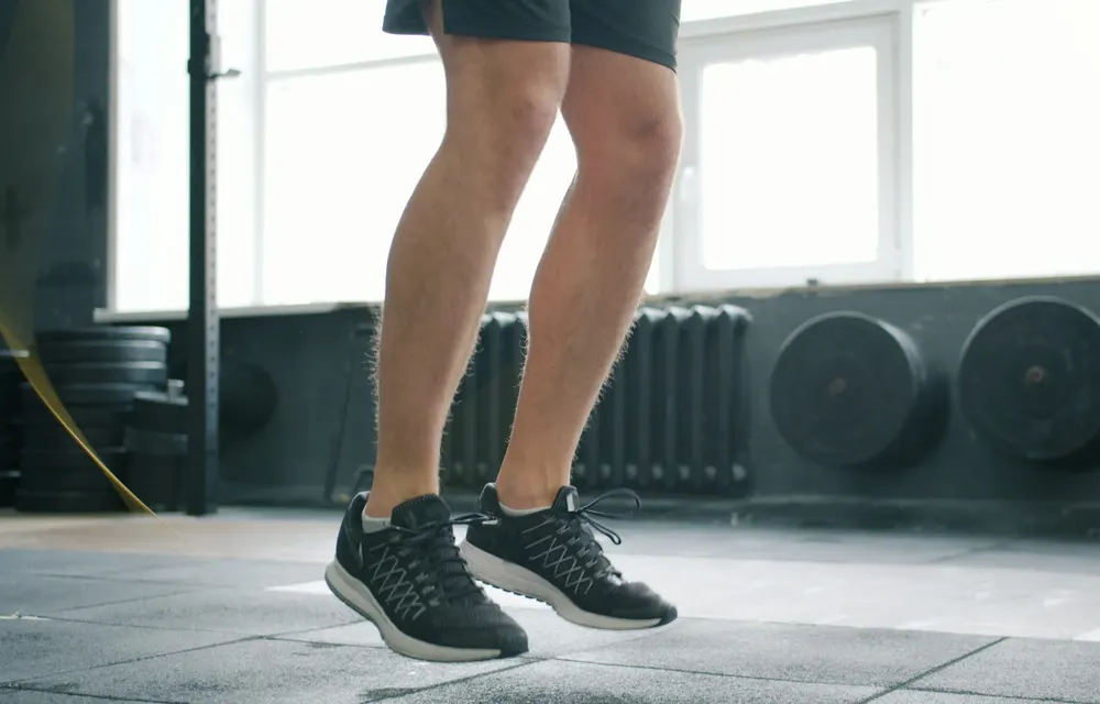 Close-up of trainers mid-jump above a rubber gym floor